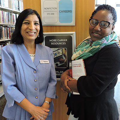 Adult Education and Job Seekers Librarian Rashmi Swain and Trina Wade pose in front of the Career Resources section.