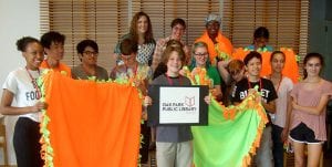 Teen Summer Volunteers hold up blankets they made for donation in 2017