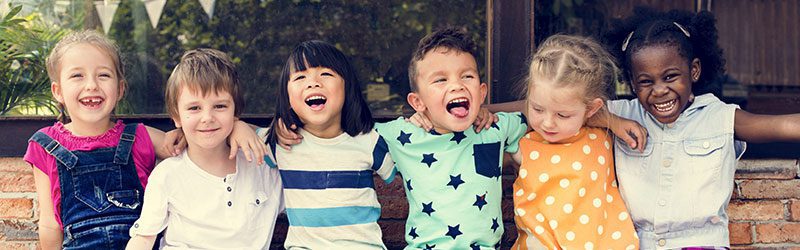 Kindergartners with linked arms on a bench