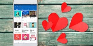 Hoopla romance audiobooks on a phone, sitting on a table next to paper hearts
