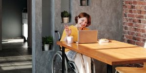 Person in wheelchair waiving at laptop