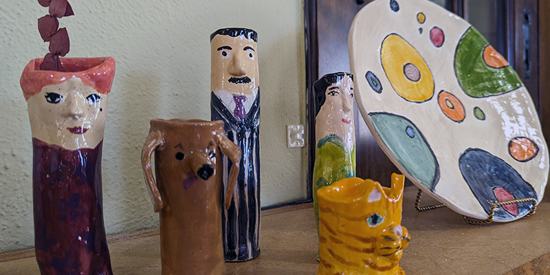 Glazed ceramic art figures of three people, a dog, and a cat, and a platter