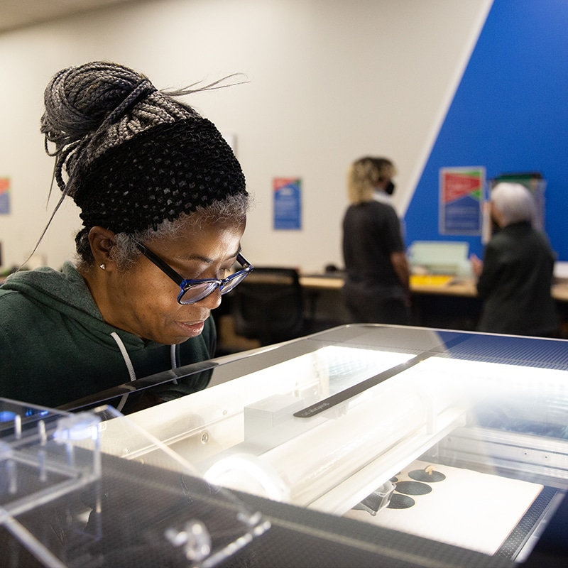 Patron looks at the Glowforge laser cutter in the library's Creative Studio