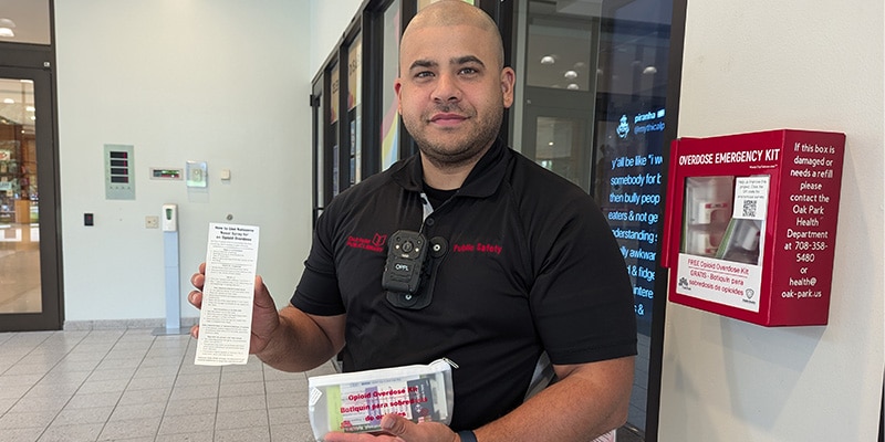 Public Safety employee holding a pouch containing naloxone and a bookmark with instructions