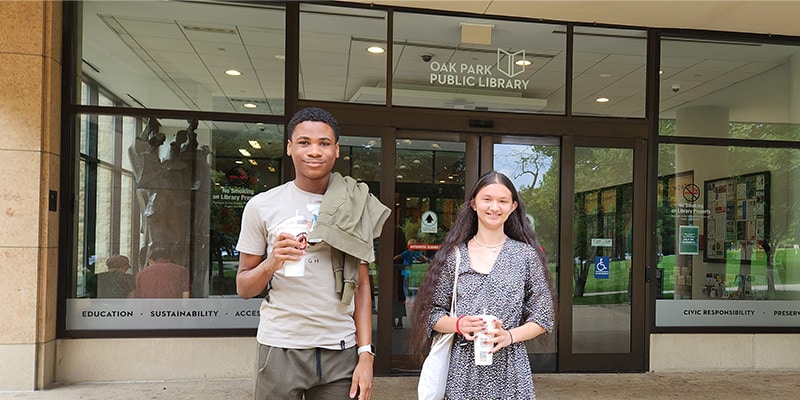 Two interns stand outside the library entrance