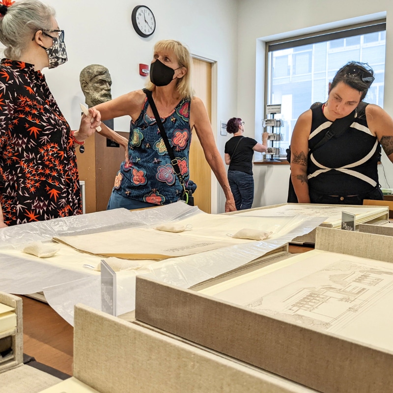 People looking at architectural drawings and talking in a library room