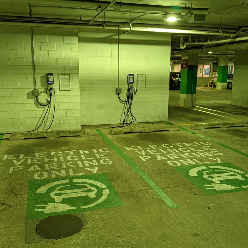 Parking spots marked with "Electric Vehicle Parking Only" signage and chargers on the wall