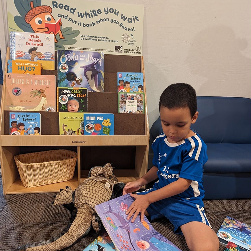 Child sits on the floor and looks at a book next to a bookshelf