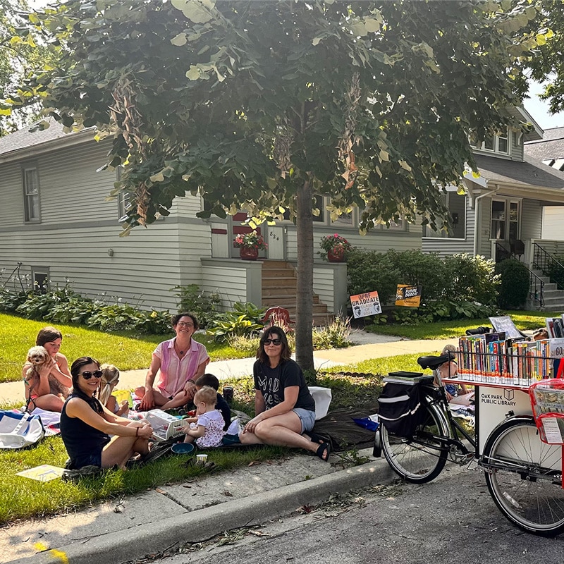 Group of neighbors gathered curbside next to a book bike